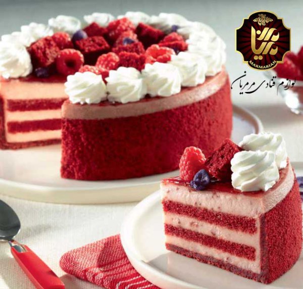 یک کیک خامه ای قرمز دارای توت های قرمز بر روی یک دیس در کنار یک تکه کیک بر روی یک ظرف