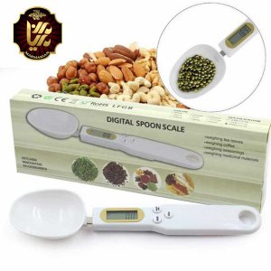 یک ترازو دیجیتال قاشقی در کنار جعبه خودش و انواع مغزیجات