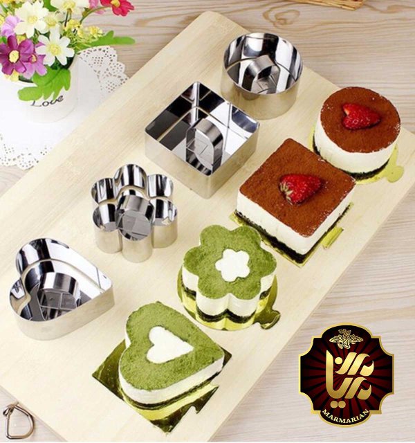 چند نوع قالب کیک به همراه تعدادی کیک شکلاتی خامه ای که بر روی ظرف های مختلف بر روی یک میز کنار یک گلدان قرار دارند